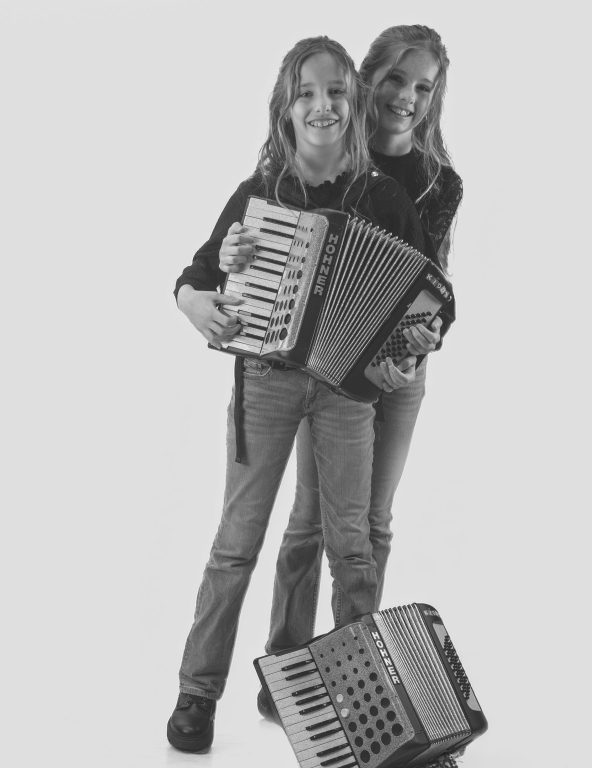 zusje omhelst ander zusje die accordeon beet heeft