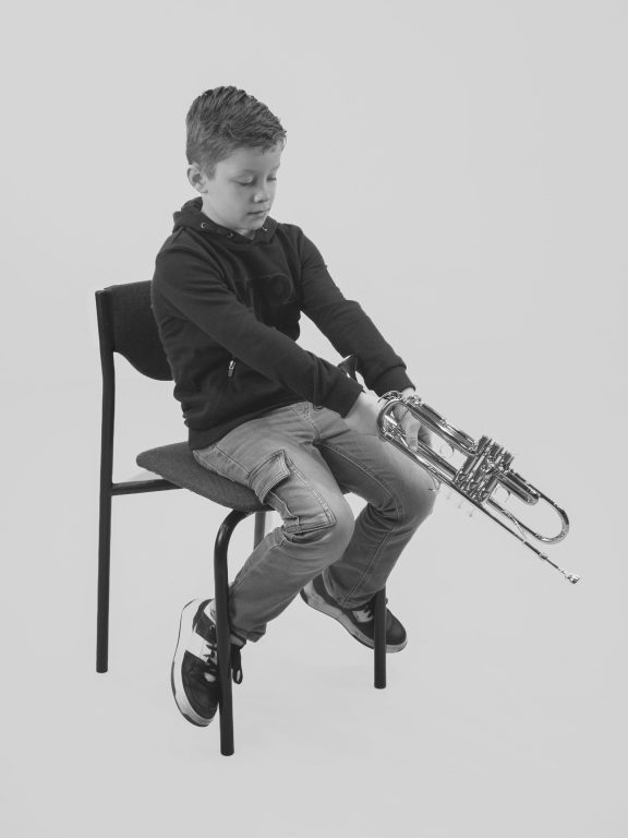 jongen zit op stoel en doet alsof hij vist met trompet