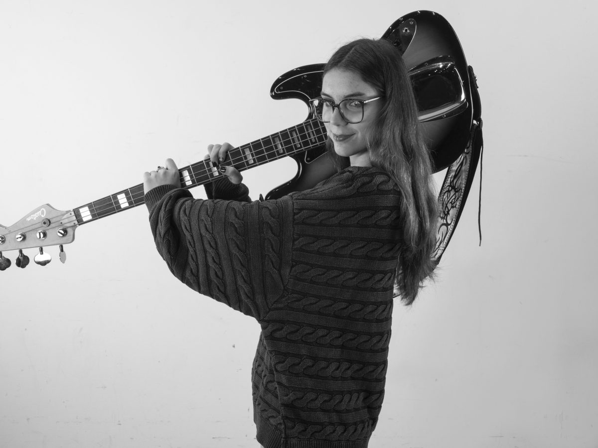 grappige foto jongedame poserend met basgitaar op schouder